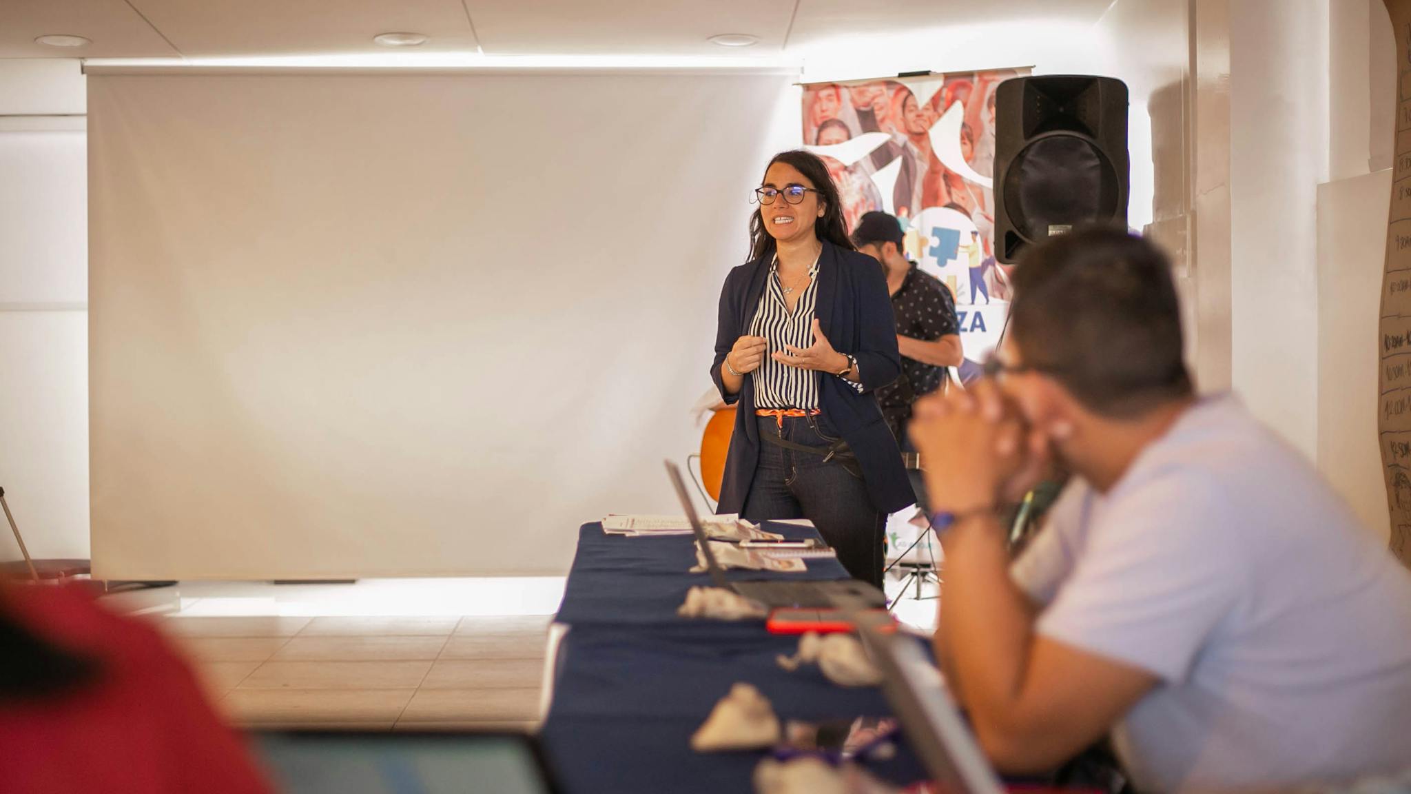 A businesswoman presents confidently during an office meeting with attentive colleagues.