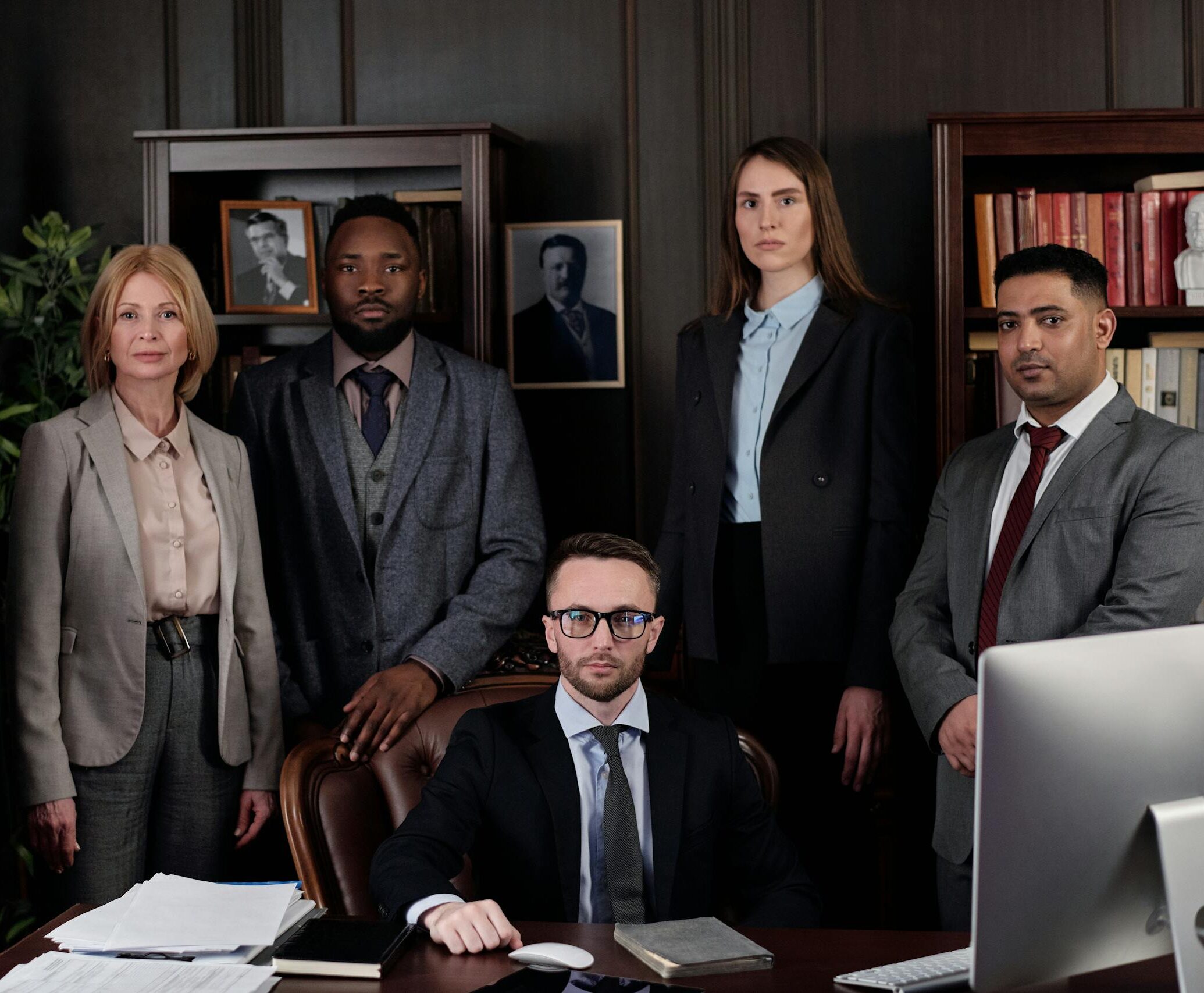 A diverse group of business professionals posing in an office, showcasing teamwork and leadership.