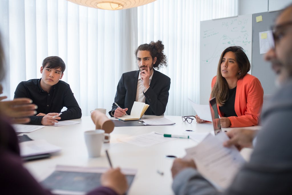 A focused business team engaged in a meeting in a well-lit, modern conference room.